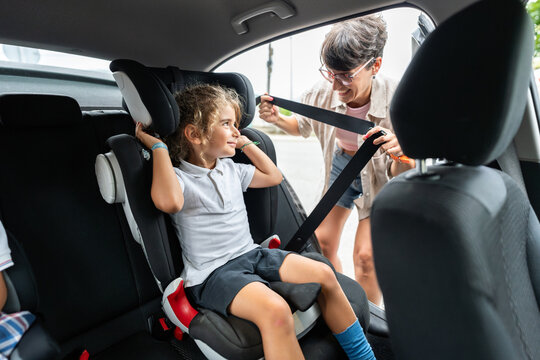 Mother fastening seat belt for daughter going to school
