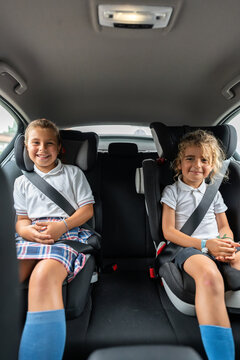 Two elementary students smiling and going to school by car
