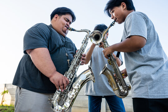 Three Musicians Playing Saxophones and Trumpet Outdoors
