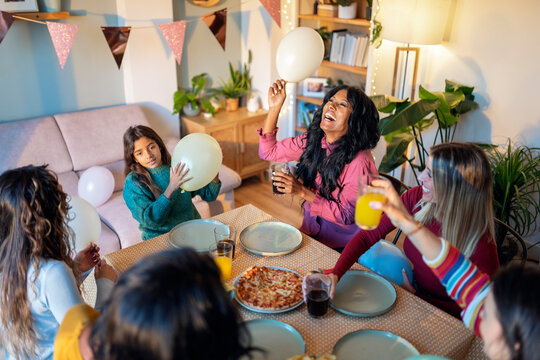 Family celebrating with balloons and pizza at home