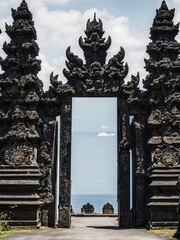 An ancient temple gate with intricate carvings and dark stone architecture, surrounded by lush greenery. A mystical and historical landmark that reflects Southeast Asian cultural heritage