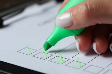 Woman checking box of paper form at table, closeup