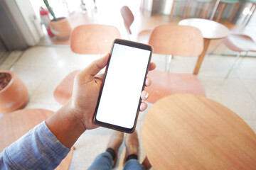 Hand holding smartphone in a modern cafe setting