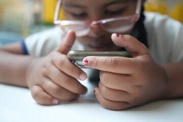 Obraz premium Child focused on smartphone while sitting indoors