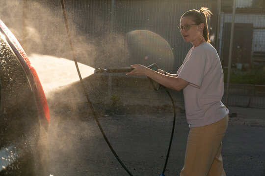 Woman Using Pressure Washer Outdoors
