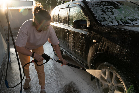 Woman Washing Car Wheel with Pressure Washer