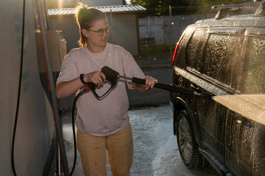 Woman Pressure Washing Car Exterior