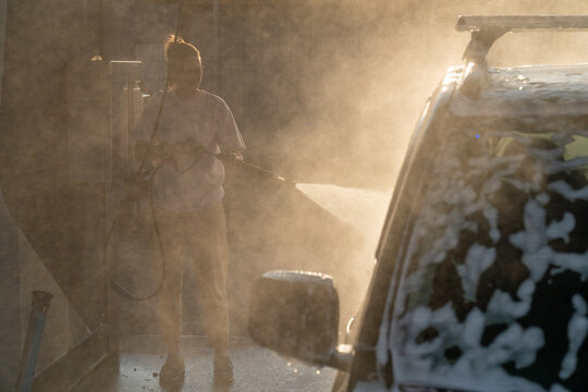 Woman Power Washing Car in Sunlit Mist