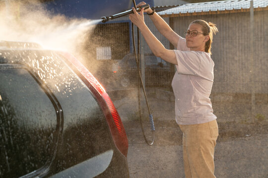 Woman Using Pressure Washer on Car