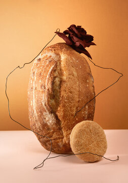 Natural still life with bread and rose on brown and pink background. 