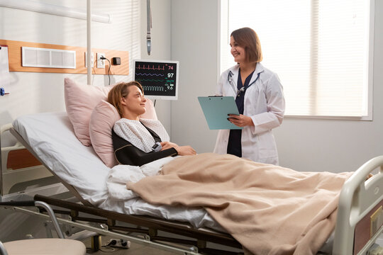 Doctor visiting patient in hospital room discussing medical chart