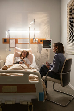 Doctor visiting patient in hospital room taking notes