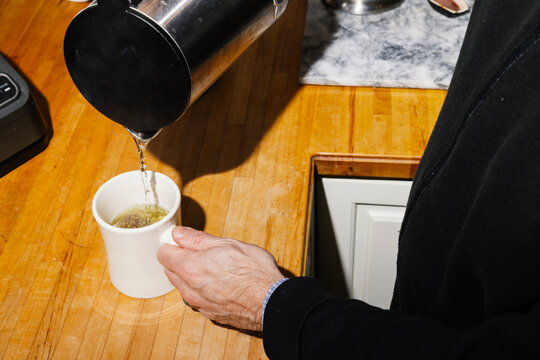 Man pouring hot water from electric kettle to make tea