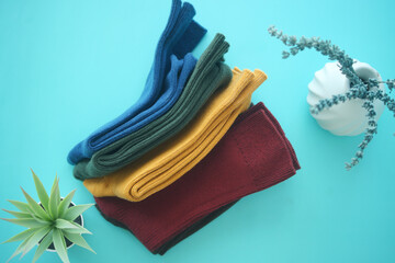 Colorful folded socks arranged on a bright blue surface with plant