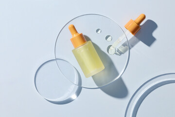 Bottle of cosmetic serum and petri dishes with samples on light 