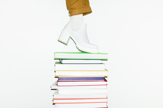 Stack of books and person with heels standing on it. Modern office 