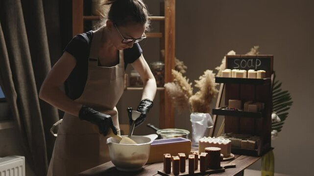 Person mixes the soap mass in the process of making soap. The master mixes the ingredients in the workshop