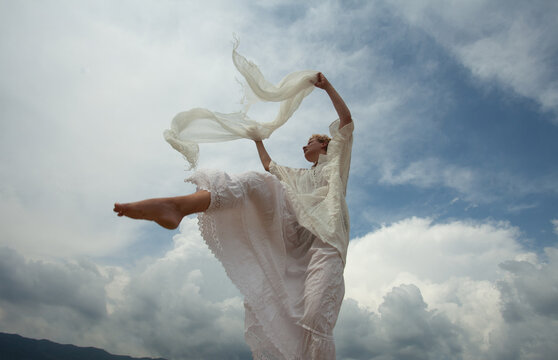 A girl in the white dress in the cloudy sky 