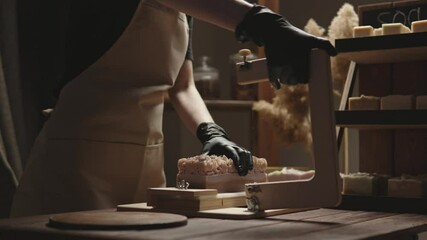 Soap maker cuts handmade berry soap with milk on a wooden cutter. Home production of natural cosmetics in the workshop