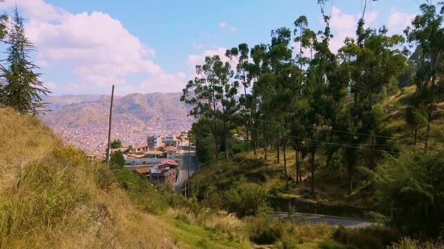 Panoramic view towards the city of Cusco, with eucalyptus trees and high altitude mountains. Trek towards ruins outside city of Cuzco