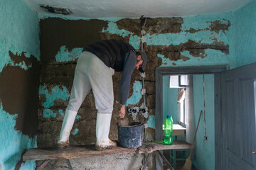 Worker rebuilds adobe wall.