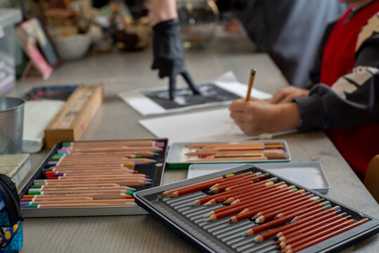 Faceless Child drawing with pencils at the table