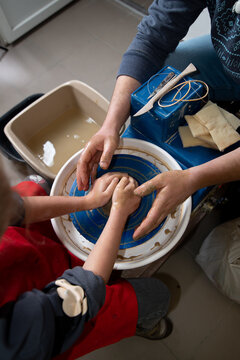 Children's and adults' hands in clay, clay plate on a potter's wheel