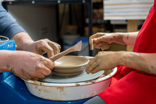 Master and a child make a clay plate on a potter's wheel