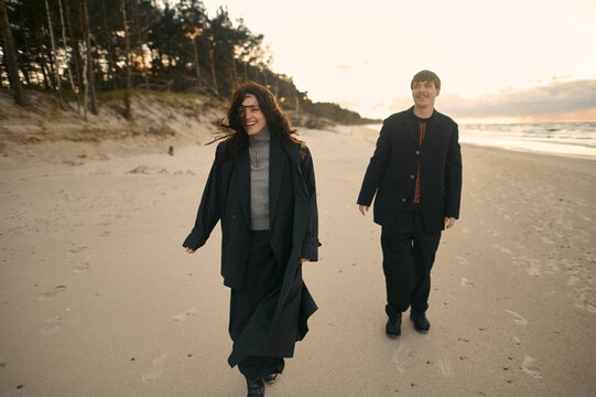 Young smiling couple on a sandy beach at sunset