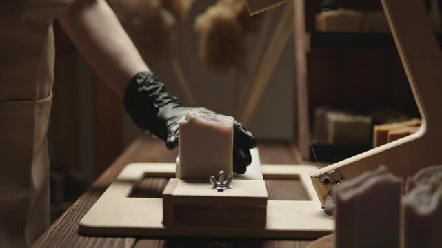 A woman master soap maker cuts handmade lavender soap on a wooden string cutter. Home production of natural cosmetics