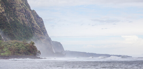 Epic cliffs of north Kohala Coast of Hawaii, a place where view ever visit. Waterfalls cascade 1000ft off the cliffs into the wild ocean waves below. Tropical green foliage clings to the cliffs.