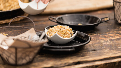 A tapa of creamy rice, risotto with mushrooms and cheese, on a board and mini paella pans, served as an appetizer during a wedding party