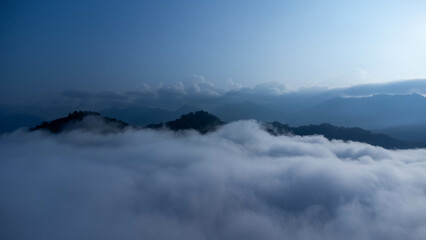 The mountain range with visible silhouettes seen through the colorful fog in the morning.