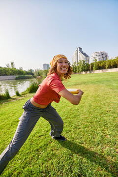 Cheerful woman throwing disc in park