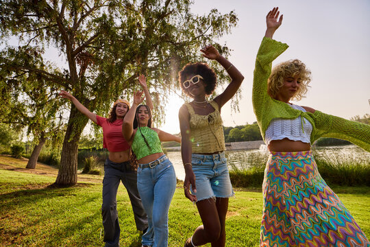 Happy diverse women dancing in park