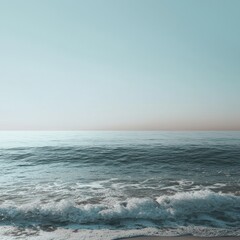 Person standing on beach holding surfboard with ocean waves and clear sky in background
