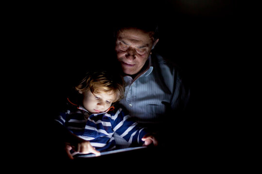 Grandfather and child sharing a quiet moment with a tablet