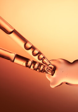 Close up of a pipette dispensing liquid on orange yellow background.