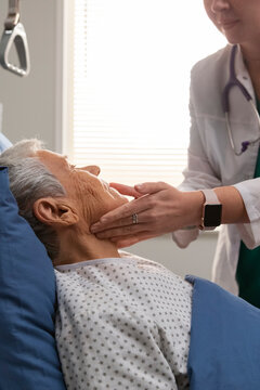Doctor examining a senior man lying in a hospital bed
