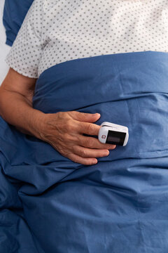 Senior patient using pulse oximeter in hospital bed measuring