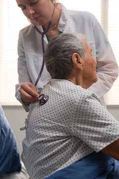 Female doctor examining elderly patient's lungs stethoscope