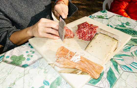 UGC Anonymous woman cutting sausages and cheese at a picnic - Powered by Adobe