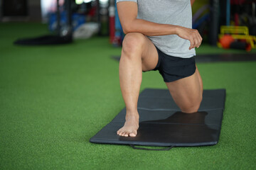 Naklejka premium Asian man stretching while in gym.