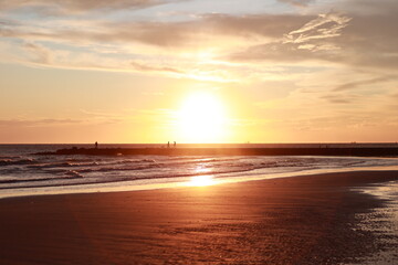 Beautiful sunset over the ocean with people walking on the beach