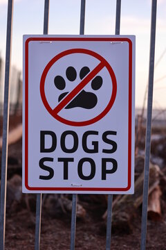 Sign that says "Dogs Stop" is on a fence