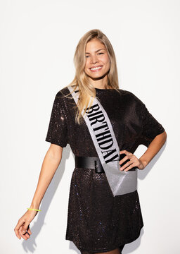 Cheerful woman celebrating birthday with a smile and sash