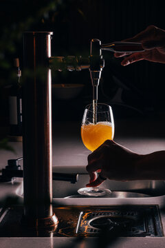 Beer being poured into a glass in a dimly lit bar setting