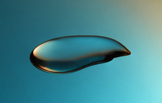Droplet of fluid gel on blue and yellow gradient backdrop.