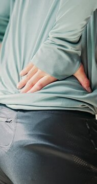 Back pain, hands and person in home, sore and injury on spine with tension, inflammation and muscle. Accident, workout and athlete with ache, body and uncomfortable with sprain, posture and hurt