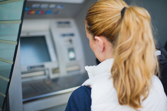 Young woman using ATM in urban location during daytime